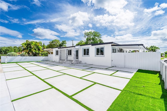 rear view of house with a patio and a lawn