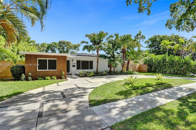 ranch-style house featuring a front lawn and solar panels