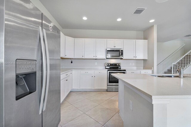 kitchen featuring white cabinetry, sink, appliances with stainless steel finishes, and light tile patterned floors