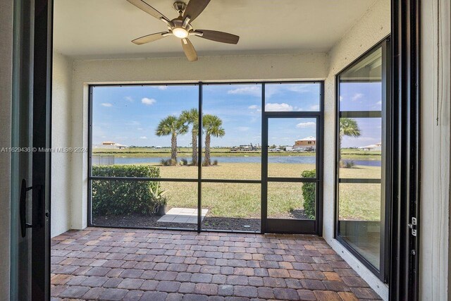 unfurnished sunroom featuring plenty of natural light, a water view, and ceiling fan