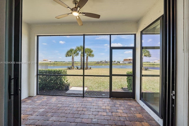 unfurnished sunroom with a water view and ceiling fan