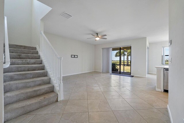 stairway with plenty of natural light, light tile patterned flooring, and ceiling fan