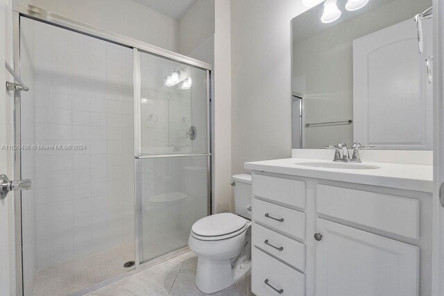 bathroom featuring a shower with shower door, vanity, tile patterned floors, and toilet