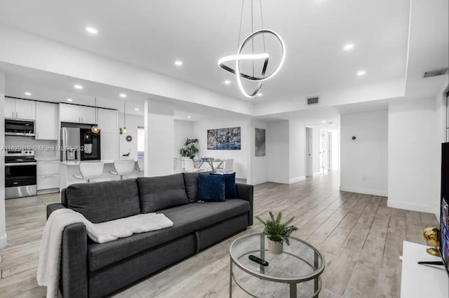 living room with a notable chandelier and light hardwood / wood-style flooring