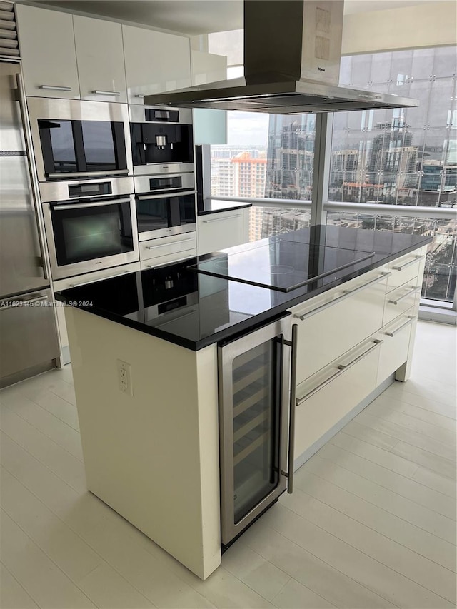 kitchen featuring exhaust hood, white cabinets, wine cooler, and a center island