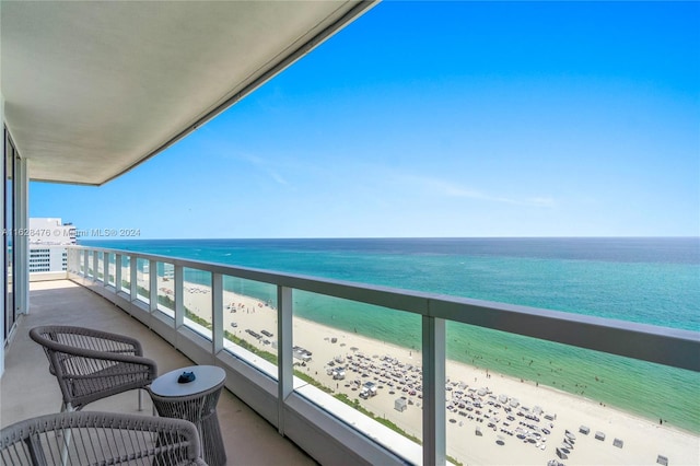 balcony featuring a view of the beach and a water view