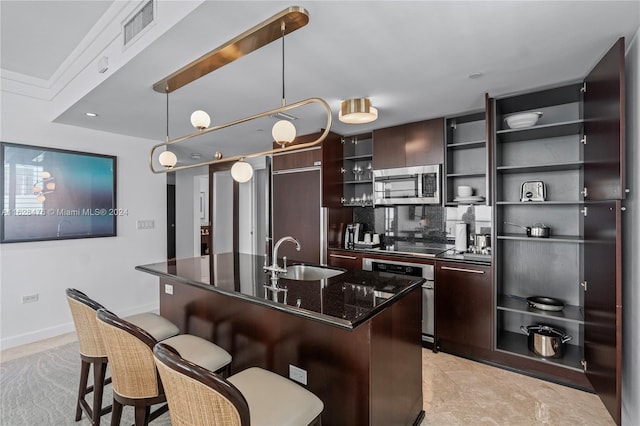 kitchen with dark stone counters, appliances with stainless steel finishes, dark brown cabinets, hanging light fixtures, and sink