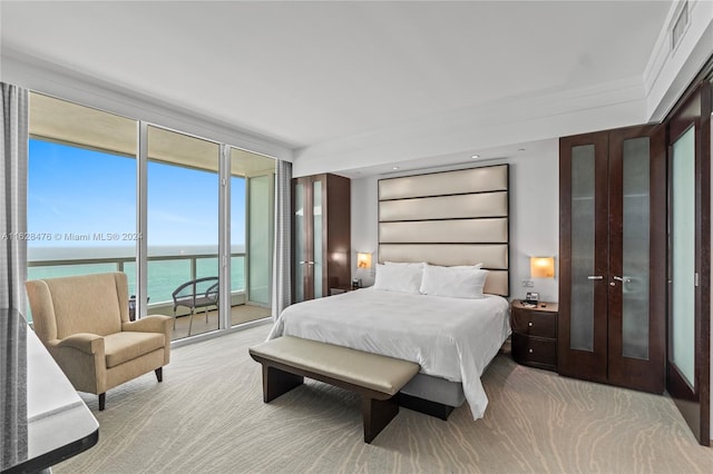 carpeted bedroom featuring access to outside, a wall of windows, a water view, and crown molding