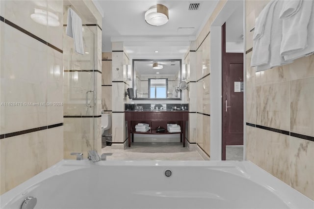 bathroom with a shower with door, vanity, toilet, and tile walls