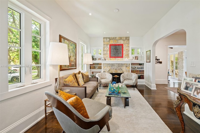 living room with a fireplace, plenty of natural light, and dark wood-type flooring