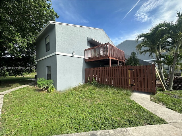 view of side of property with a deck and a lawn