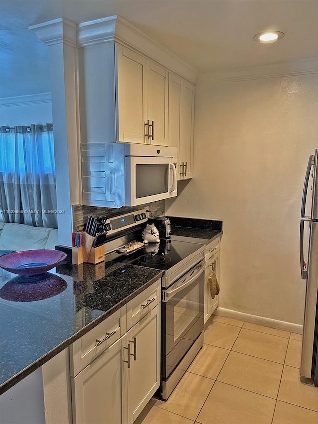 kitchen with white cabinetry, dark stone countertops, light tile patterned floors, stainless steel appliances, and decorative backsplash