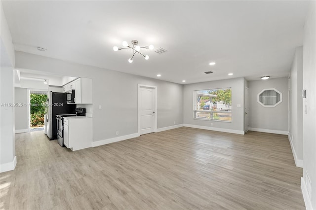 unfurnished living room with a chandelier and light hardwood / wood-style floors