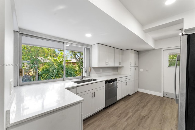 kitchen featuring appliances with stainless steel finishes, white cabinetry, a healthy amount of sunlight, and sink