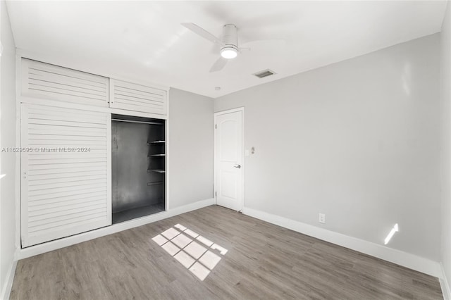 unfurnished bedroom featuring ceiling fan, wood-type flooring, and a closet