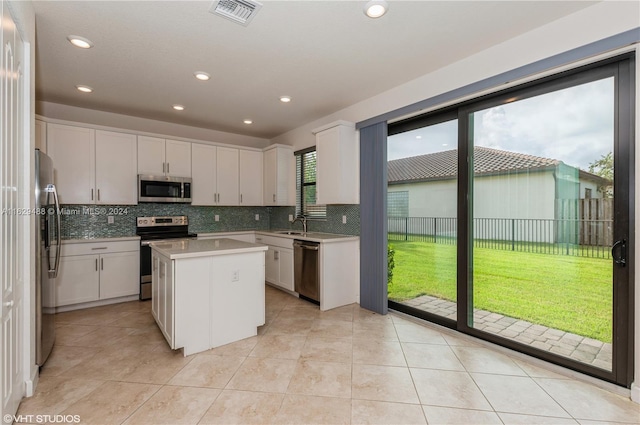 kitchen with a kitchen island, appliances with stainless steel finishes, a healthy amount of sunlight, and white cabinets