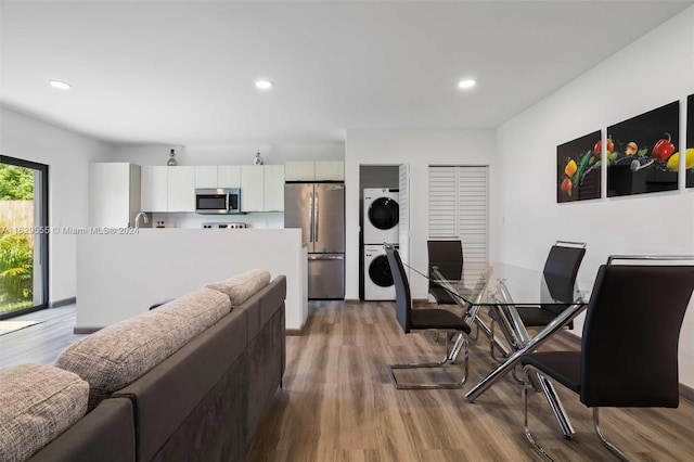 dining area with stacked washing maching and dryer and light hardwood / wood-style floors