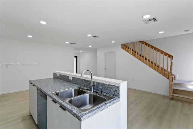 kitchen featuring dishwasher, sink, light wood-type flooring, and a kitchen island with sink