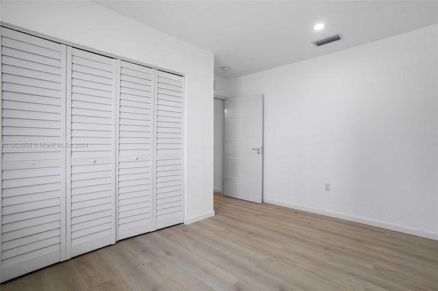 unfurnished bedroom with light hardwood / wood-style flooring and a closet