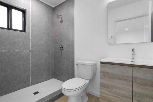 bathroom with tiled shower, vanity, and toilet