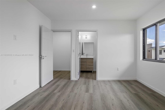 unfurnished bedroom with light wood-type flooring and connected bathroom