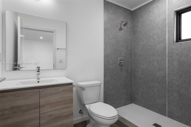 bathroom featuring vanity, toilet, and tiled shower