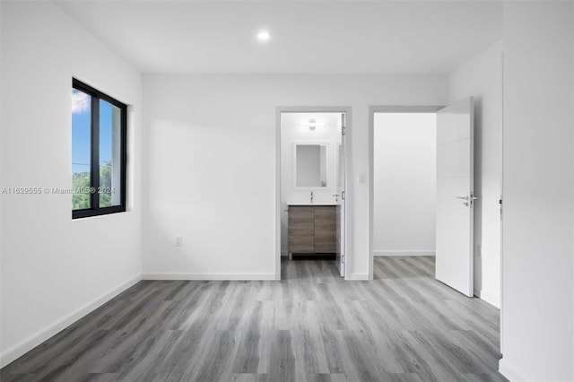 unfurnished bedroom featuring ensuite bathroom, a closet, a spacious closet, and light hardwood / wood-style flooring