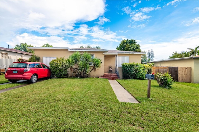 view of front of property with fence, a front lawn, and stucco siding