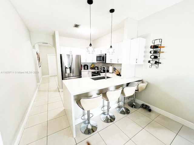 kitchen with appliances with stainless steel finishes, decorative light fixtures, sink, white cabinets, and kitchen peninsula