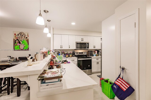 kitchen with pendant lighting, a breakfast bar area, white cabinetry, appliances with stainless steel finishes, and light stone countertops