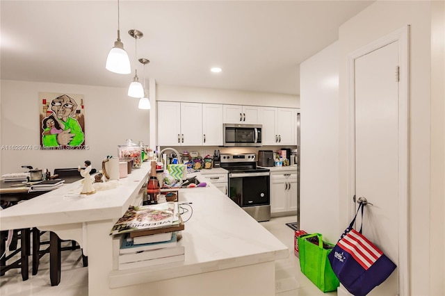 kitchen with pendant lighting, sink, appliances with stainless steel finishes, a kitchen breakfast bar, and white cabinets