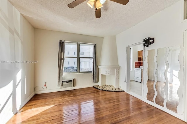 empty room featuring ceiling fan, a wall unit AC, light tile patterned floors, and a textured ceiling