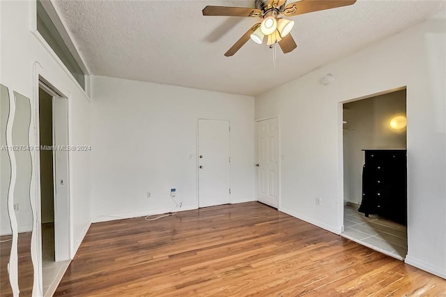 unfurnished bedroom with hardwood / wood-style flooring, a textured ceiling, and ceiling fan