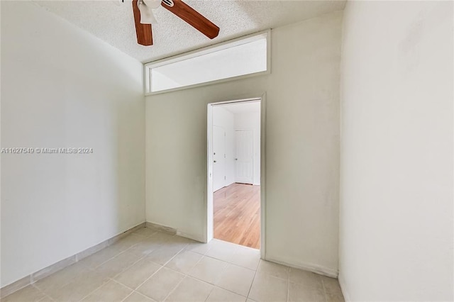 tiled empty room featuring a textured ceiling and ceiling fan