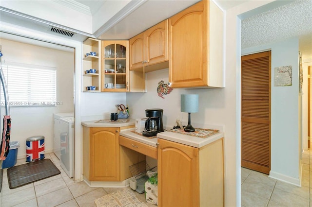 kitchen with washing machine and dryer, light brown cabinets, a textured ceiling, and light tile patterned floors