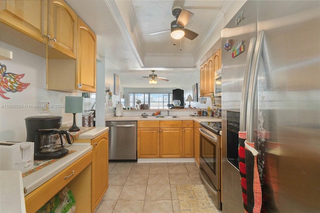 kitchen with light tile patterned flooring, ornamental molding, appliances with stainless steel finishes, and a raised ceiling