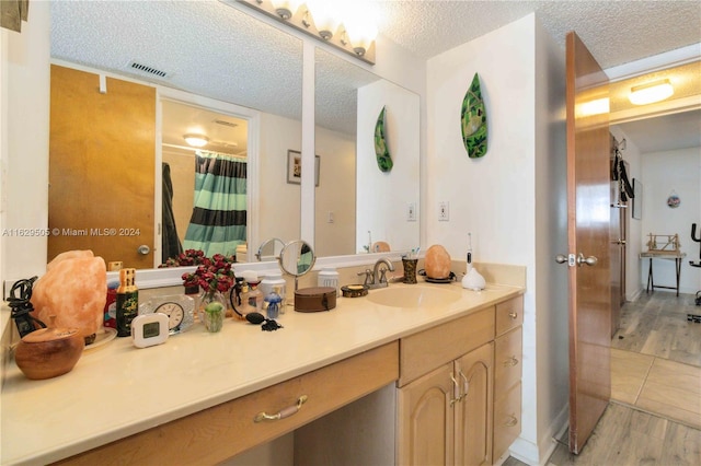 bathroom with wood-type flooring, curtained shower, a textured ceiling, and vanity