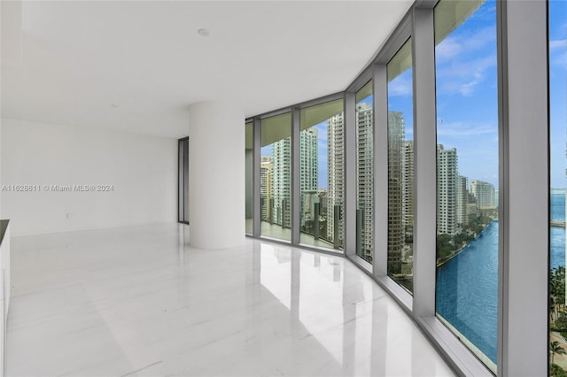 unfurnished room featuring a water view and a wall of windows