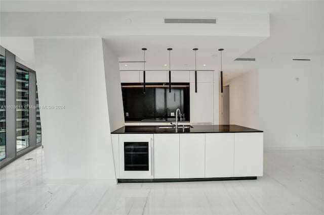 kitchen with white cabinetry, wine cooler, sink, and hanging light fixtures