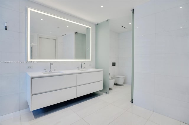 bathroom with tile patterned floors, toilet, tile walls, a bidet, and vanity