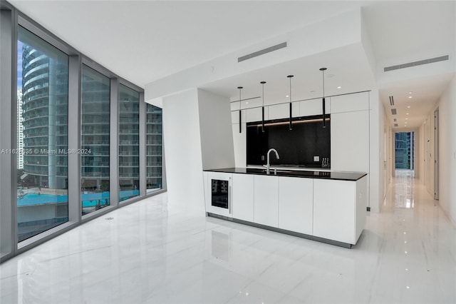 kitchen featuring white cabinetry, beverage cooler, floor to ceiling windows, and decorative light fixtures