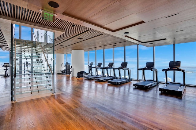 gym featuring floor to ceiling windows, hardwood / wood-style flooring, wood ceiling, and a healthy amount of sunlight