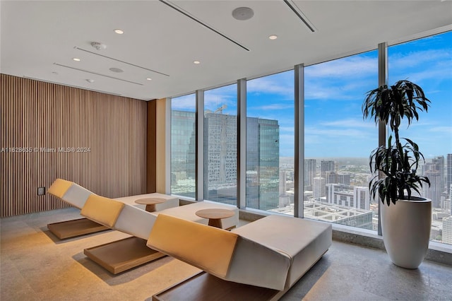 interior space featuring floor to ceiling windows, wooden walls, and a healthy amount of sunlight