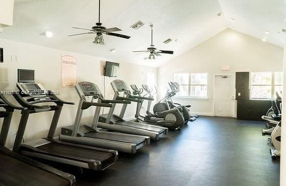 gym with high vaulted ceiling and ceiling fan