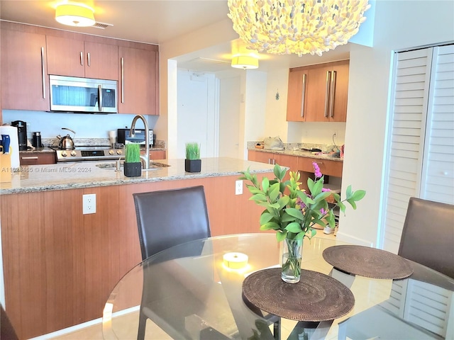 kitchen featuring stainless steel appliances, light stone countertops, and a chandelier