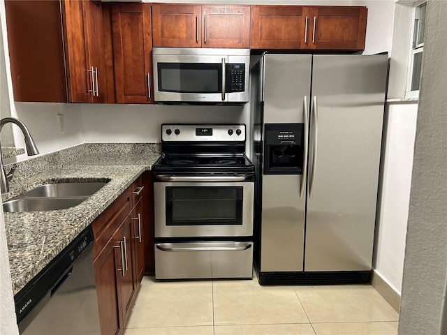 kitchen with sink, stone countertops, light tile patterned floors, and stainless steel appliances