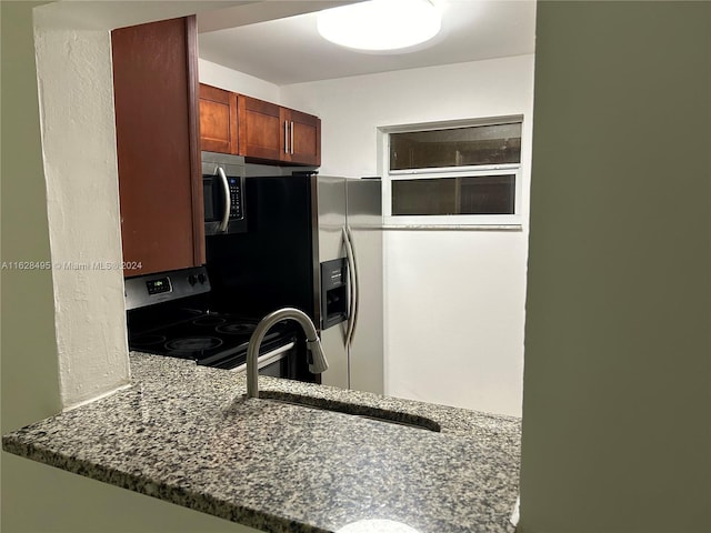 kitchen featuring sink, dark stone counters, and appliances with stainless steel finishes