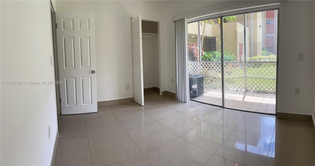 unfurnished bedroom featuring access to exterior, a closet, and light tile patterned floors