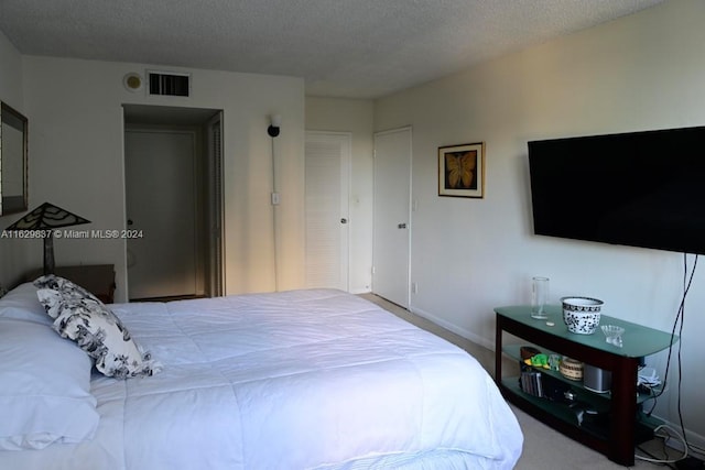 bedroom with light carpet and a textured ceiling