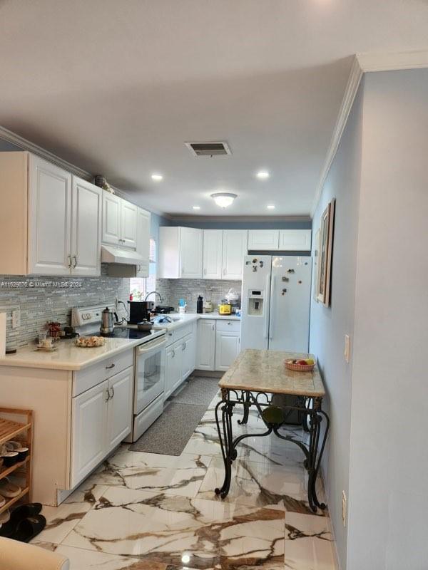 kitchen with light tile patterned flooring, decorative backsplash, white cabinets, and white appliances